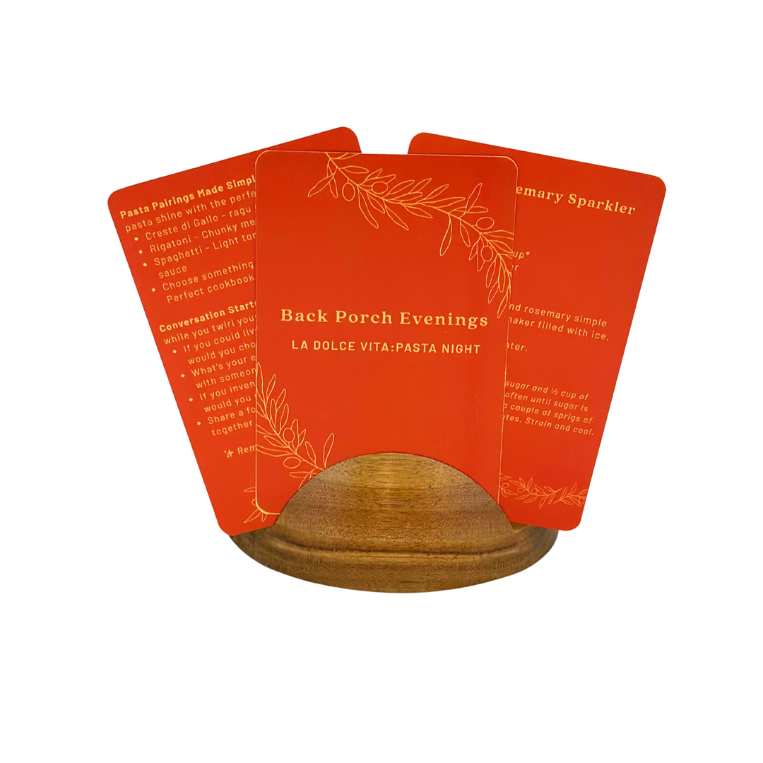 Set of red, Back Porch Evenings La Dolce Vita Date Night box guide cards with text in a wooden stand on a white background