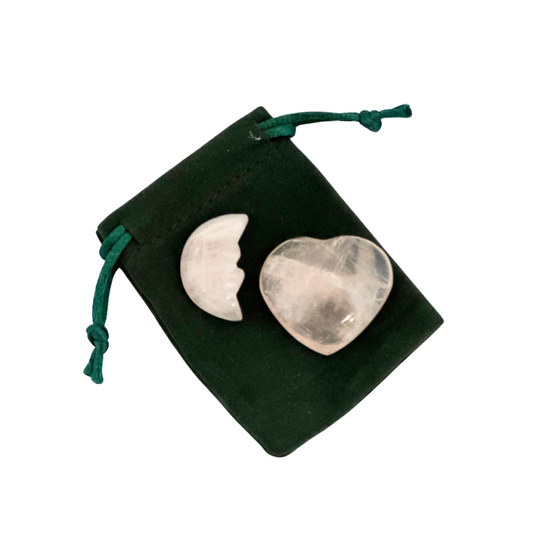 Heart and moon -shaped rose quartz stones on a green velvet pouch with a white background
