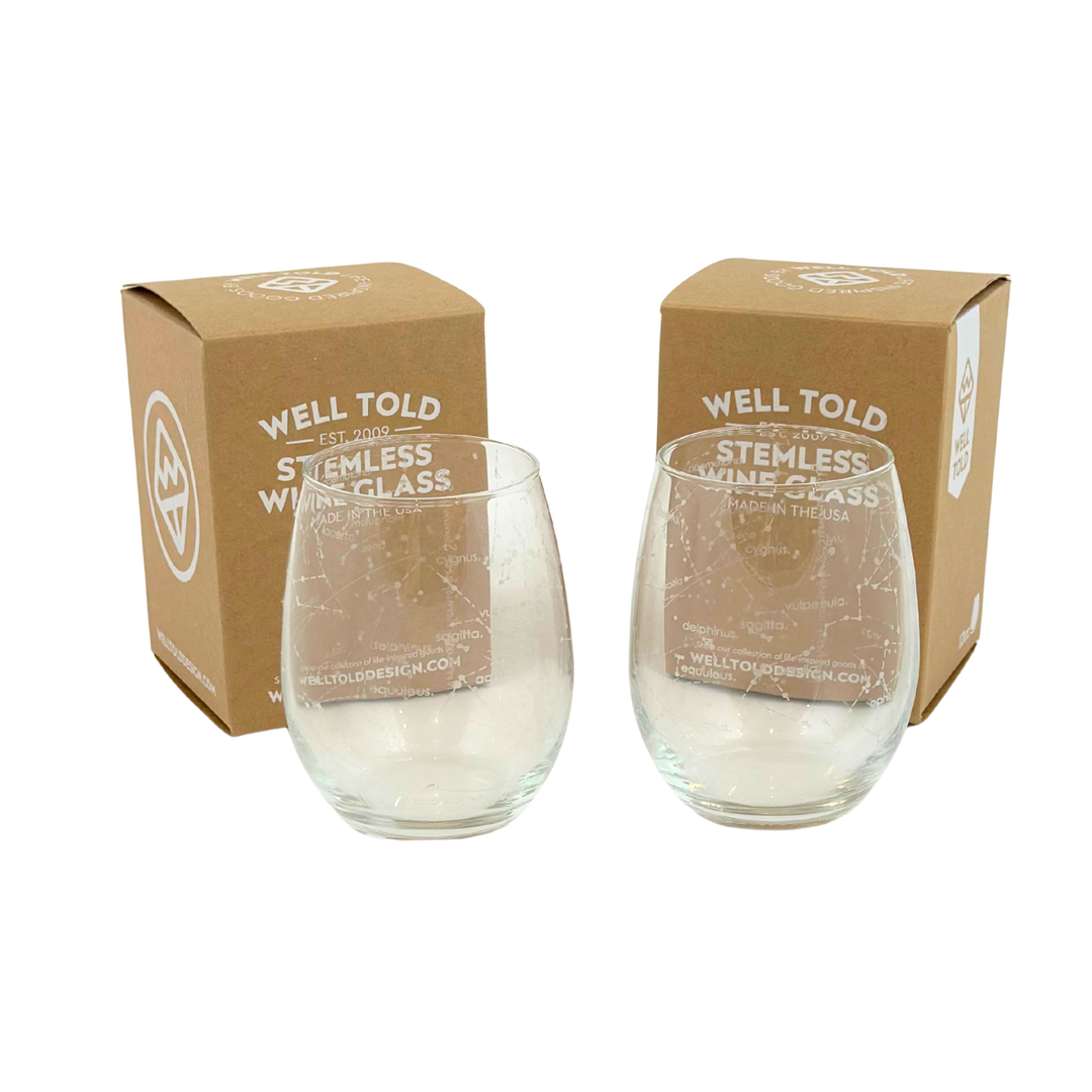 Two stemless wine glasses with constellations from 'Well Told' on a white background